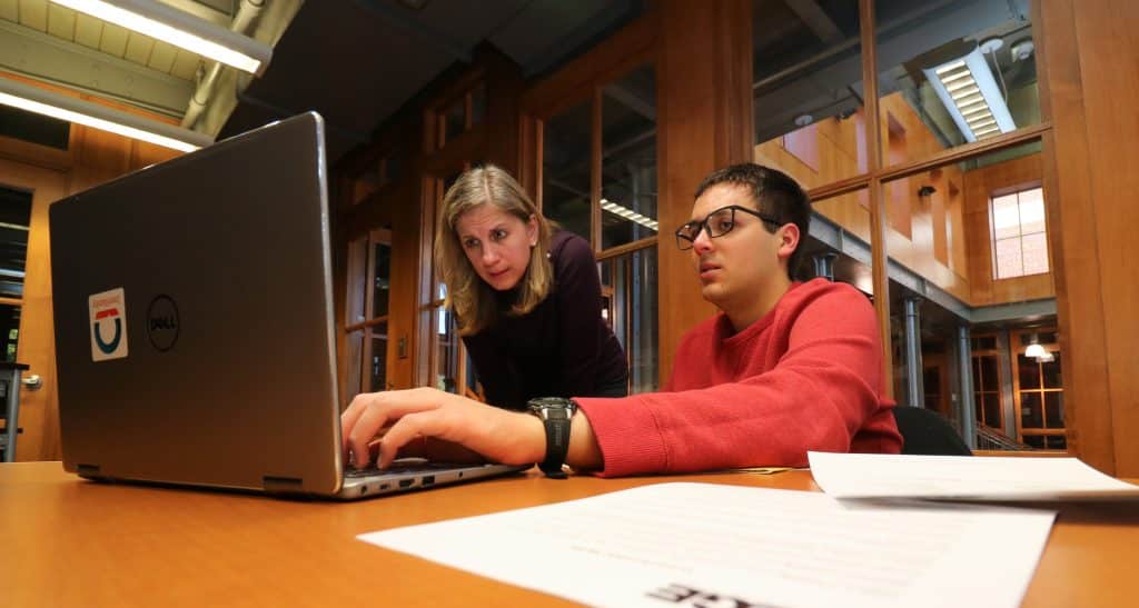 A RMC employee guides a student working on a laptop during a resume writing workshop in the Edge Career Center