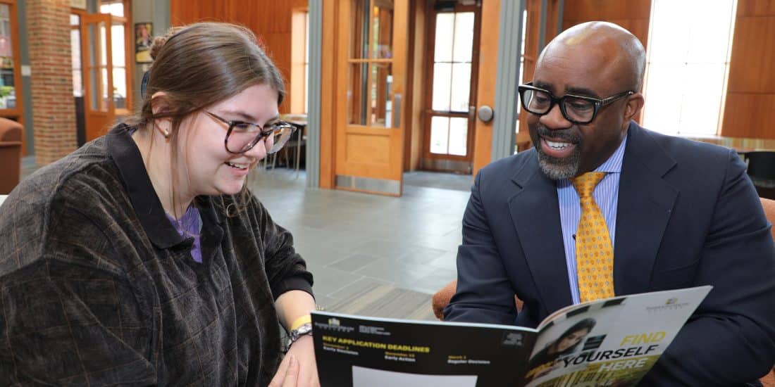 Admissions counselor, Gabe Raynor, reviews a brochure on admissions and aid with a student.